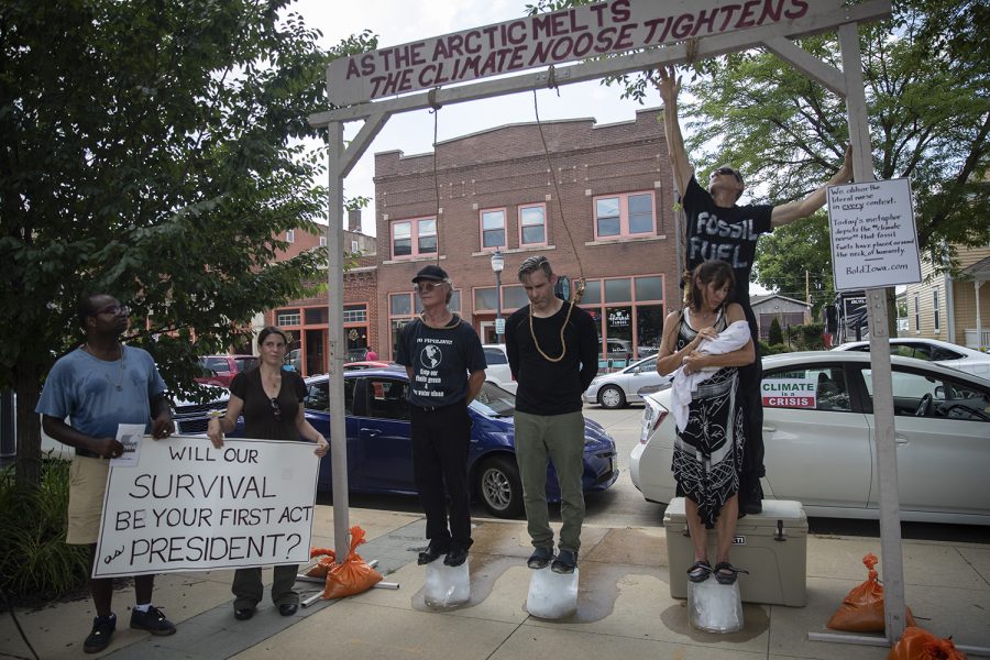 Demonstrators protest climate change action outside of the Progress Iowa Corn Feed in Newbo City Market in Cedar Rapids on July 14, 2019. 10 candidates came to meet supporters and give speeches. Demonstrators stood on a block of ice with nooses around their necks. 