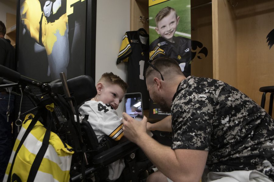 Kid Captain Cien Currie watches as his dad opens gifts placed at his locker in the Hawkeye Football locker room at Kids Day at Kinnick on Saturday, August 10, 2019. Kids Day at Kinnick is an annual event for families to experience Iowa's football stadium, while watching preseason practice and honoring this year's Kid Captains. (Ryan Adams/The Daily Iowan)