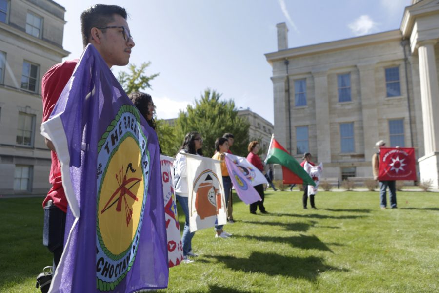Rally attendees hold flags representing various Native American tribes during the decolonization rally on the Pentacrest on Monday, Oct. 15, 2019. The rally featured speakers and music. 