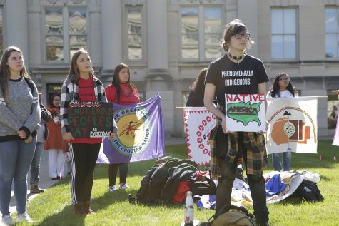 Rally attendees hold signs during the decolonization rally on the Pentacrest on Monday, Oct. 15, 2019. The rally featured speakers and music. 