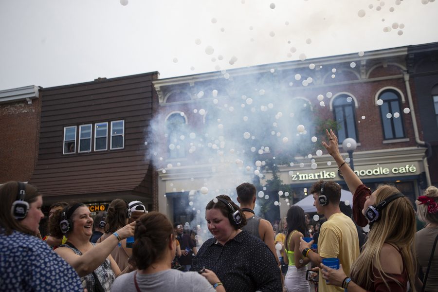 Emmy Knutsson reaches for bubbles at the silent disco during Block Party in downtown Iowa City on June 22, 2019. Several blocks of Iowa City were reserved for games, performances and vendors. 