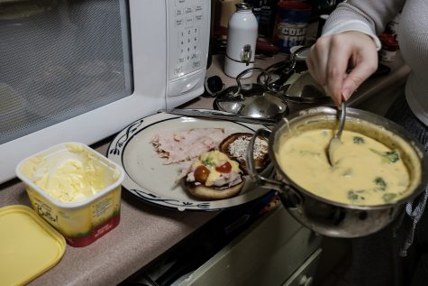 The Daily Iowan Arts reporter Addie Bushnell cooks a cheese sauce for the “Hot Turkey Sandwich” recipe from The Original Recipes of Bushnell’s Turtle. 