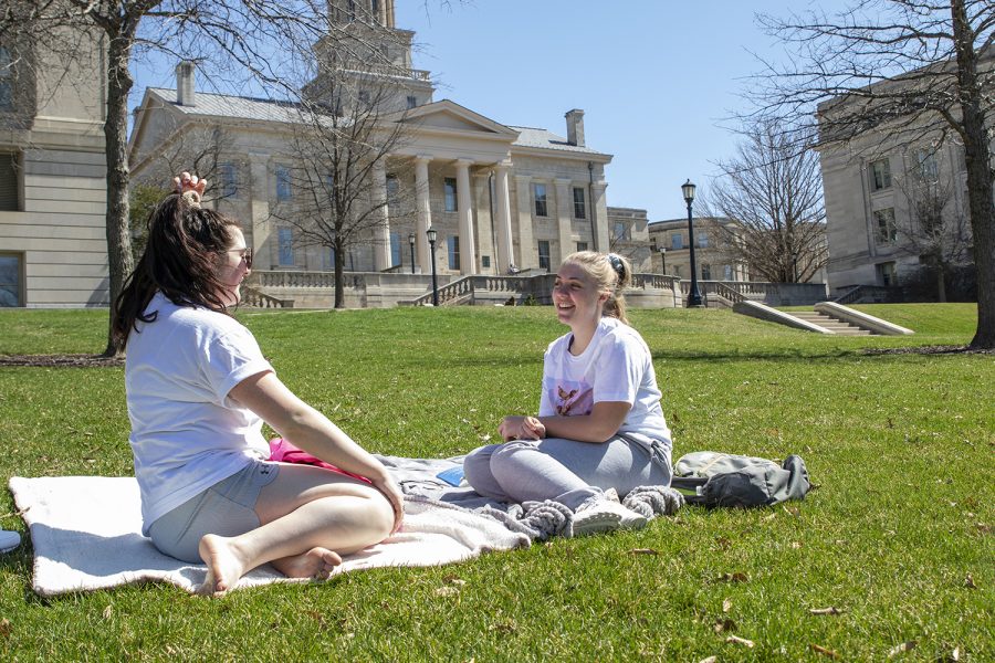 UI juniors Bailey Fitzgibbon (left) and Holly Dannen sit on the Pentacrest on Monday March 30, 2020. Campus was empty as students began their first day of online classes. 