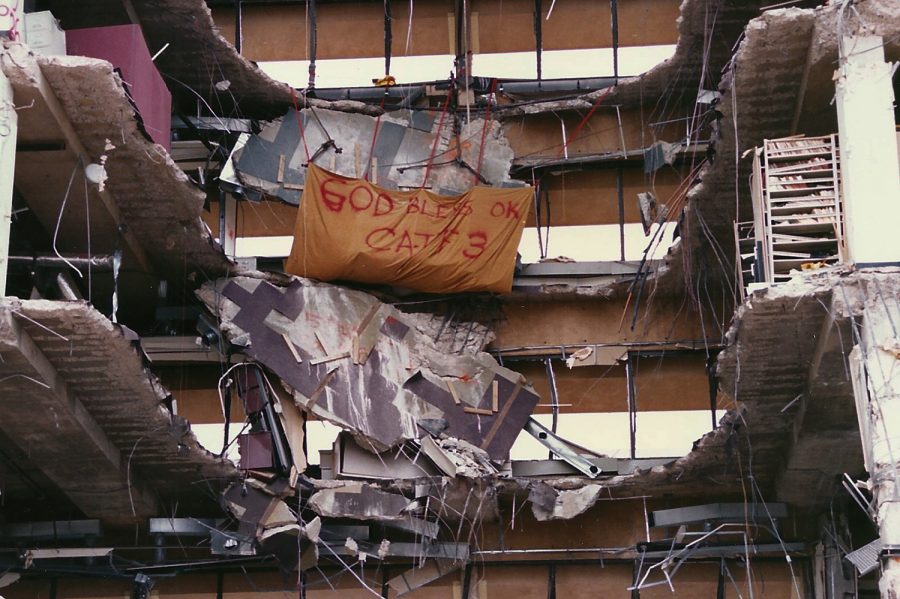 A banner hangs from what remains of the Alfred P. Murrah Federal Building’s north side in the weeks following a domestic terrorist attack in 1995. In the aftermath of the Oklahoma City bombing, a makeshift memorial was established at the base of the structure. 