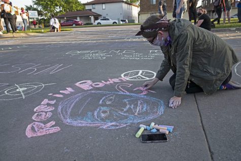 A young woman draws a portrait of George Floyd during chalk the walk outside of the Coralville Police Department on Monday, June 22, 2020.