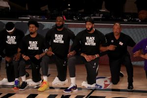 The Los Angeles Lakers, including LeBron James and Anthony Davis, wear Black Lives Matter shirts while kneeling during the national anthem prior to a game against the Los Angeles Clippers and head coach Doc Rivers, right, at The Arena at ESPN Wide World Of Sports Complex in Lake Buena Vista, Florida, on Friday, July 30, 2020. 