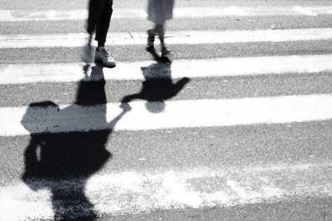 Blurry shadow and silhouette of mother and child at zebra crossing.