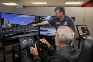Joe Meidlinger instructs Tom Beaver of Iowa City on the use of a mini sim driving simulator during an open house at the National Advanced Driving Simulator in Coralville on Wednesday Oct. 10, 2018. Meidlinger is the program supervisor for the mini sim program. Beavers son, Greg, a UI senior and mechanical engineering student, works in the mini sim program.