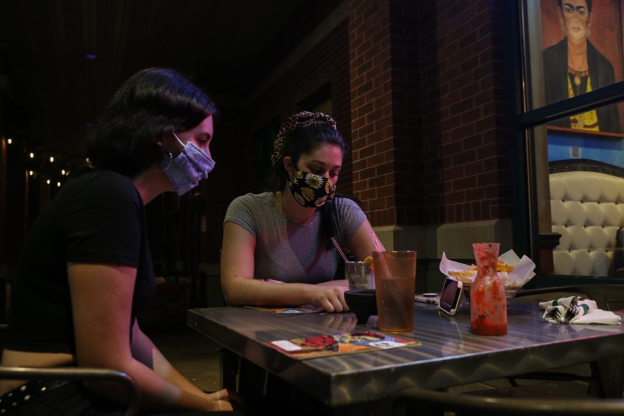 University of Iowa students Molly Fischer and Cassidy Beshel watch the second presidential debate on a phone while eating on Thursday, Oct. 22, 2020 at Casa Azul in Iowa City.