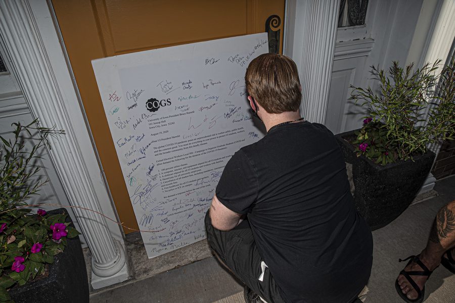 Political Action Committee Chairperson Daniel Knipp walks up to President Bruce HarreldÕs doorway to sign an open letter addressed to Harreld and the administration as part of a demonstration on Aug. 19, 2020. The Campaign to Organize Graduate Students (COGS) led a march to Harreld's home in order to protest the administration's insistence that the university remain open despite the health risk posed by COVID-19.