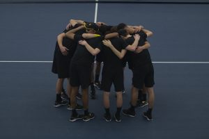 Iowa players huddle on the court before a men’s tennis match between Iowa and Louisville on Friday, March 6, 2020 at The Hawkeye Tennis Recreation Complex. The Hawkeyes defeated the Cardinals 4-1.