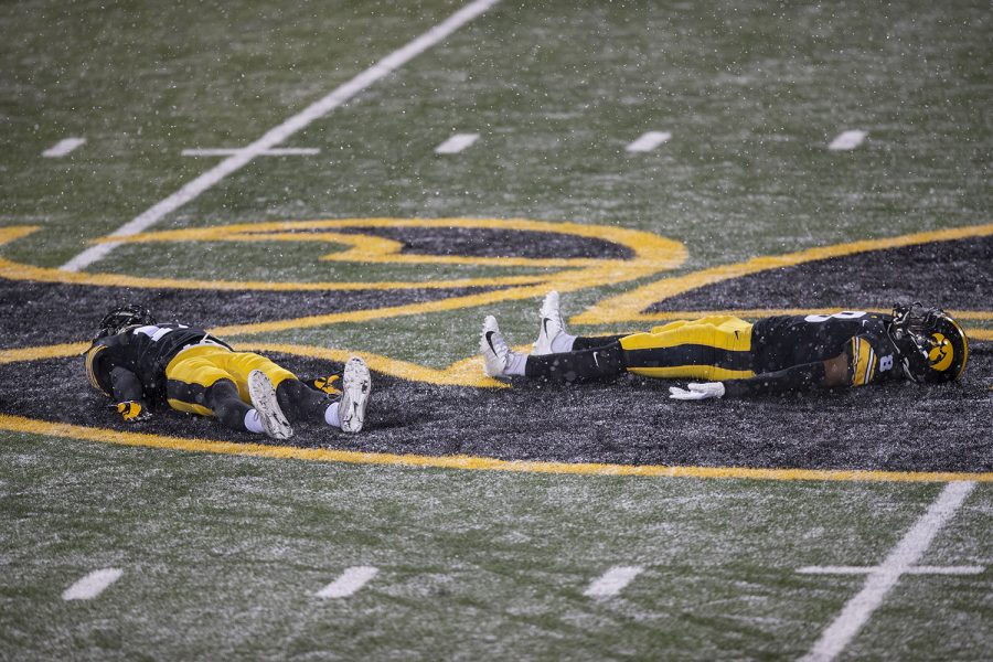 Dec. 12, 2020; Iowa City, Iowa, USA; Iowa defensive back Brenden Deasfernandes (left) and defensive back Matt Hankins (right) make snow angels on the field after the Iowa v. Wisconsin football game at Kinnick Stadium. Iowa defeated Wisconsin with a score of 28-7.