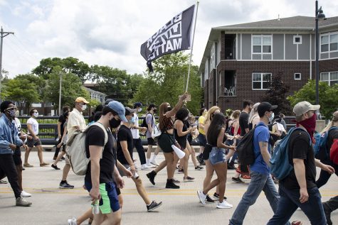 A protester walks with A Black Lives Matter flag on Saturday, June 20 on Burlington Street. The Iowa Freedom Riders hosted a celebration after the march to commemorate Juneteenth, the anniversary of when the last enslaved people were freed.