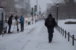 Students are seen walking to and from class in the snow while a reporter and cameraman set up equipment at the University of Iowa on Monday, Jan. 25, 2021. (Grace Smith/The Daily Iowan)
