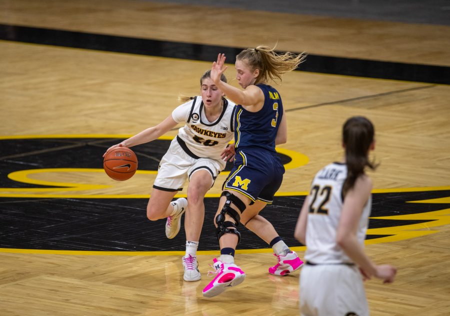Iowa Guard Kate Martin dribbles the basketball past the logo. Michigan Guard Maddie Nolan shuffles to stay in front during a womens basketball game against Michigan on Thursday, Feb. 25, 2021 at Carver Hawkeye Arena. The Hawkeyes defeated the Wolverines 89-67.