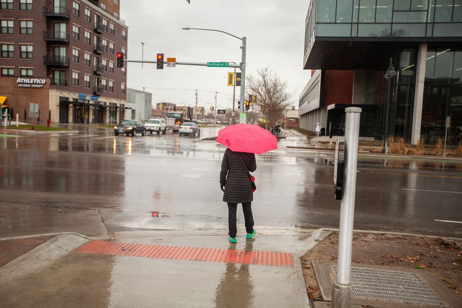 A pedestrian waits to cross West Burlington Street in Iowa City on Tuesday, March 23 as the rain continues to fall. 