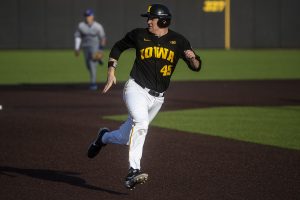 Iowa first baseman Peyton Williams watches where the ball is while racing to third base during a baseball game between the Iowa Hawkeyes and the Kansas Jayhawks on Tuesday, March 10, at Duane Banks Field. The Hawkeyes defeated the Jayhawks, 8-0. 