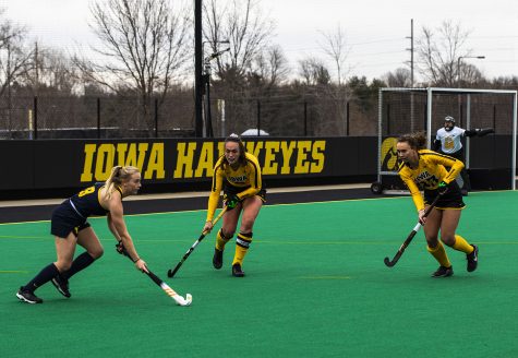 Michigan Forward Sarah Pyrtek works to move the ball around Iowa defenders Anthe Nijziel (6) and Harper Dunne (23) during a field hockey game between Iowa and Michigan at Grant Field on Saturday, March 15, 2021. “The Hawkeyes defeated the Wolverines, 2-1, in a shootout.”