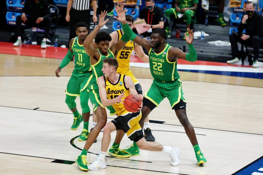 Mar 22, 2021; Indianapolis, Indiana, USA; Iowa Hawkeyes looks to pass while defended by Oregon Ducks forward Chandler Lawson (left) and center Franck Kepnang (right) during the first half in the second round of the 2021 NCAA Tournament at Bankers Life Fieldhouse. Mandatory Credit: Trevor Ruszkowski-USA TODAY Sports