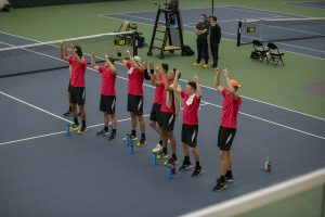 Iowa players chant and cheer on Will Davies during his singles match at the Iowa Men’s tennis meet v. Wisconsin in the Hawkeye Tennis and Recreation Complex on Friday, March. 12, 2021. The Hawkeyes defeated the Badgers 5-2.