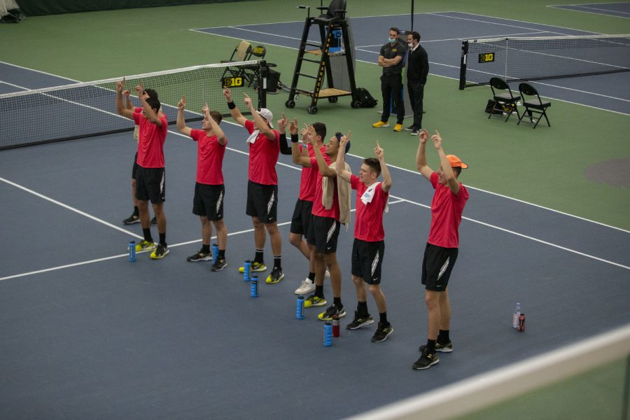 Iowa players chant and cheer on Will Davies during his singles match at the Iowa Men’s tennis meet v. Wisconsin in the Hawkeye Tennis and Recreation Complex on Friday, March. 12, 2021. The Hawkeyes defeated the Badgers 5-2.