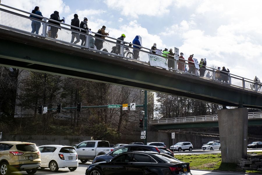 A group of people wave to cars and hold signs on the Riverside Dr. overpass on Wednesday, March 31, 2021. Iowa Citizens for Community Improvement (CCI) organized the rally to show support for workers, for climate, and for racial justice.