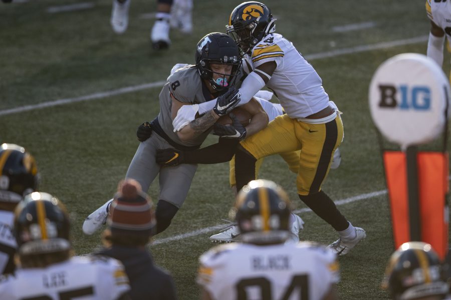 Saturday Dec. 5, 2020; Champaign, Illinois, USA; Illinois wide receiver Casey Washington (left) is tackled by Iowa defensive back Matt Hankins (right) during the second quarter of the Iowa v. Illinois football game at Memorial Stadium.