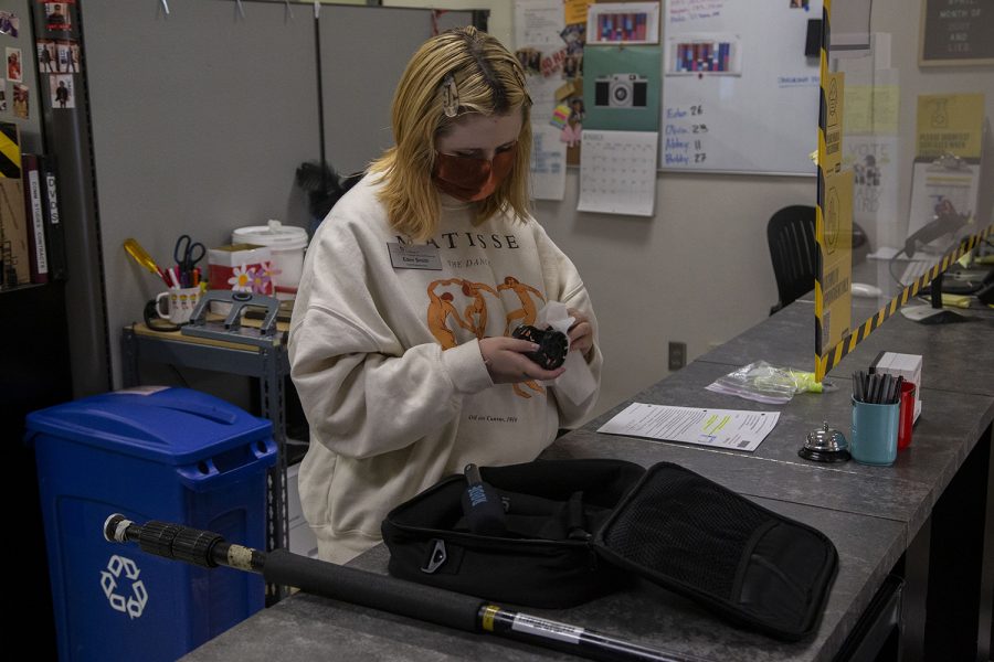 Senior and journalism major, Eden Smith, cleans equipment after a student returns it in Equipment Checkout located in the Becker Communication Studies Building at the University of Iowa on Wednesday, March 31, 2021. (Grace Smith/The Daily Iowan)