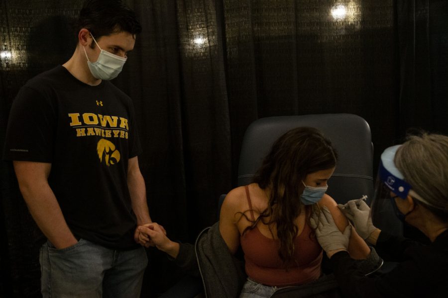 Fourth-year students, Grace Cannell and Ethan Fobbe, hold hands while Cannell receives her Pfizer COVID-19 vaccine at the Iowa Memorial Union at the University of Iowa on Wednesday, April 21, 2021. 