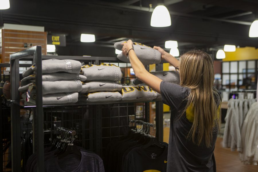 An Iowa Hawk Shop student employee places a sweatshirt on a display on Thursday, Oct. 31, 2019. 