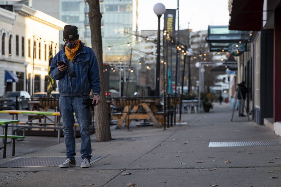 An individual waits outside before an away football game on Friday, Nov. 13, 2020 in Downtown Iowa City. 