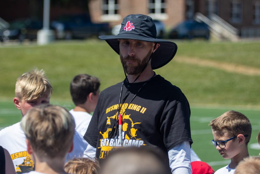 Iowa City High football coach Mitch Moore talks in a huddle during the Desmond King Football Camp at Iowa City High on Saturday, June 19, 2021. City High announced Moore as the new coach of the Little Hawks in November of 2020. 