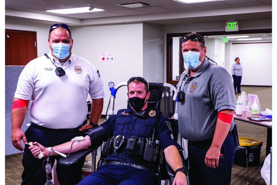 Asst. Fire Chief Nic Pruter left and Lt. William (Bill) Erb of the Coralville Fire Department stopped by to lend support to Sgt. Kyle Nicholson of the Coralville police Department on Thursday, July 22, 2021. At the time, Nicholson was donating blood during the Battle of the Badges Blood Drive.(Jeff Sigmund/Daily Iowan)
