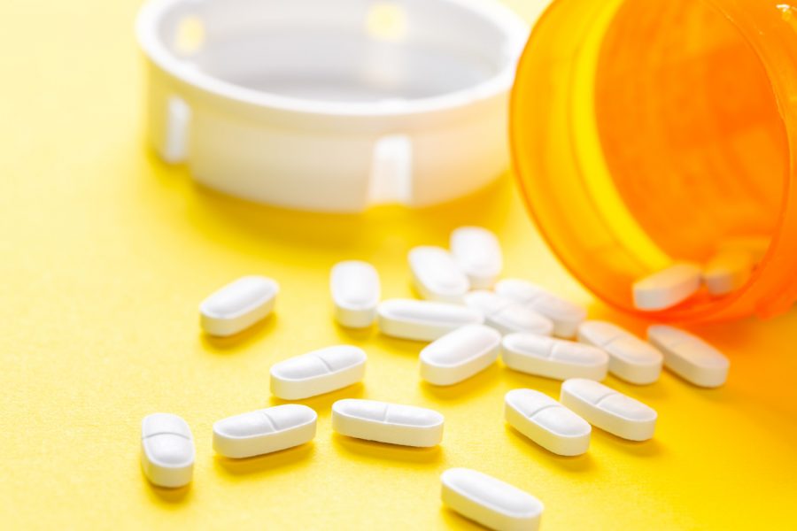 Pile+of+white+pills+or+capsules+on+yellow+background