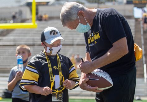 Iowa head coach Kirk Ferentz signs a ball for kid captain Kale Schmidt during “Kid’s Day at Kinnick” inside Kinnick Stadium on Saturday, Aug. 14.
