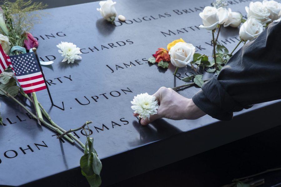A citizen puts a flower in a victim’s name at the 9/11 Memorial in New York City on Saturday, Sept.11, 2021, the 20th anniversary of the 9/11 attacks.