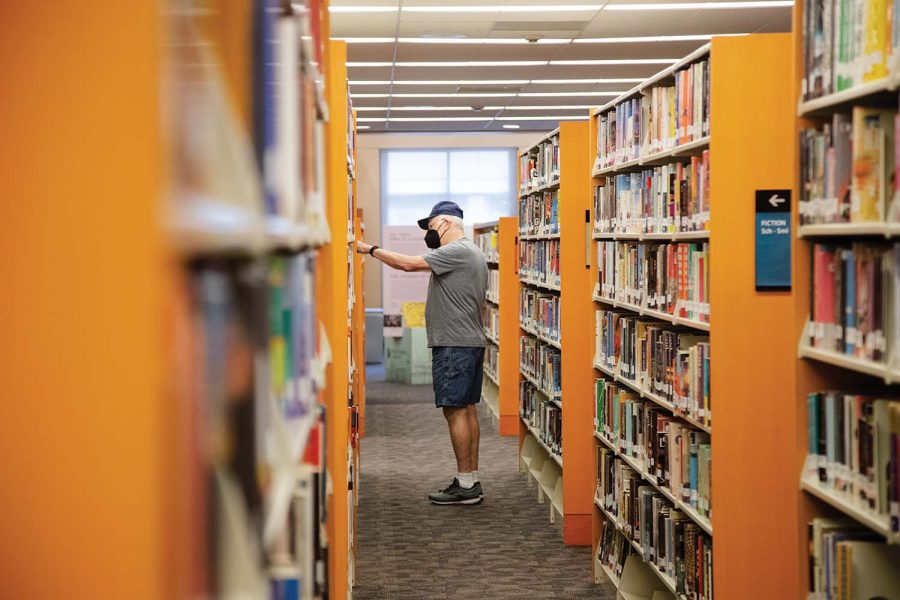 A masked visitor picks out a book at the Iowa City Public Library on Monday, Sept. 27, 2021. 