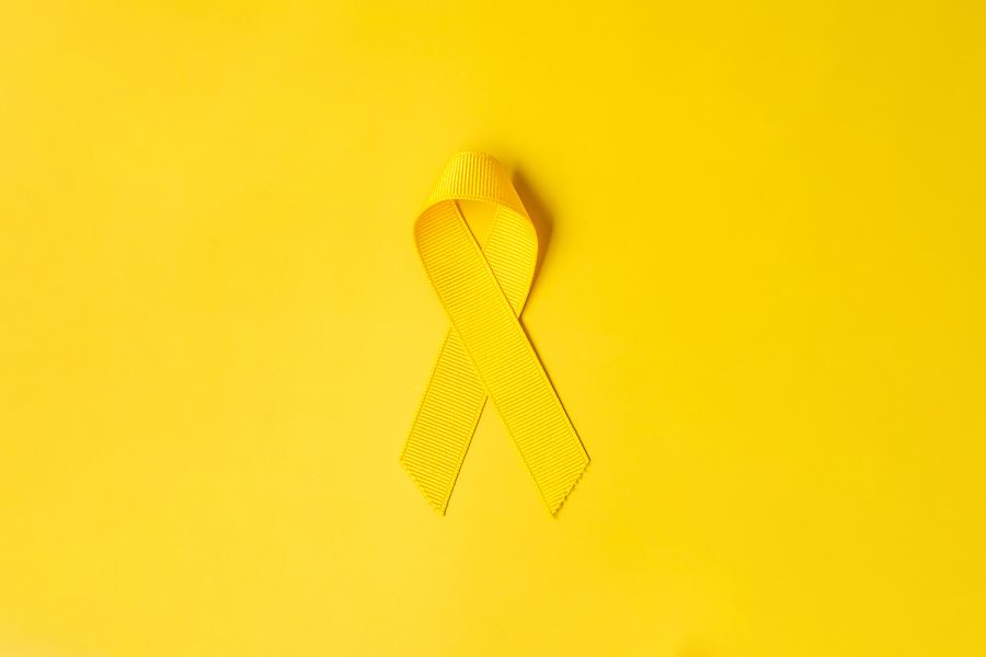 Yellow Ribbon on yellow background for supporting people living and illness. September Suicide prevention day, Childhood Cancer Awareness month and World cancer day concept