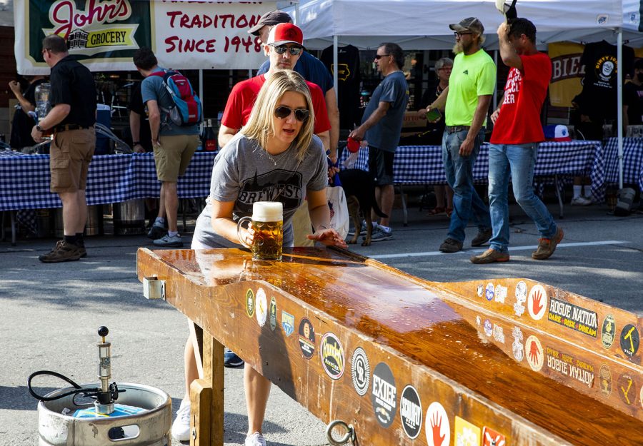 Anna Hawken try the “Mug Slide” at the 25th BrewFest/6th Annual Northside Oktoberfest on Saturday, Oct. 2, 2021. Contestants try to slide a bug filled with beverage down a makeshift bar with out spilling any of the contents.(Jeff Sigmund/Daily Iowan)