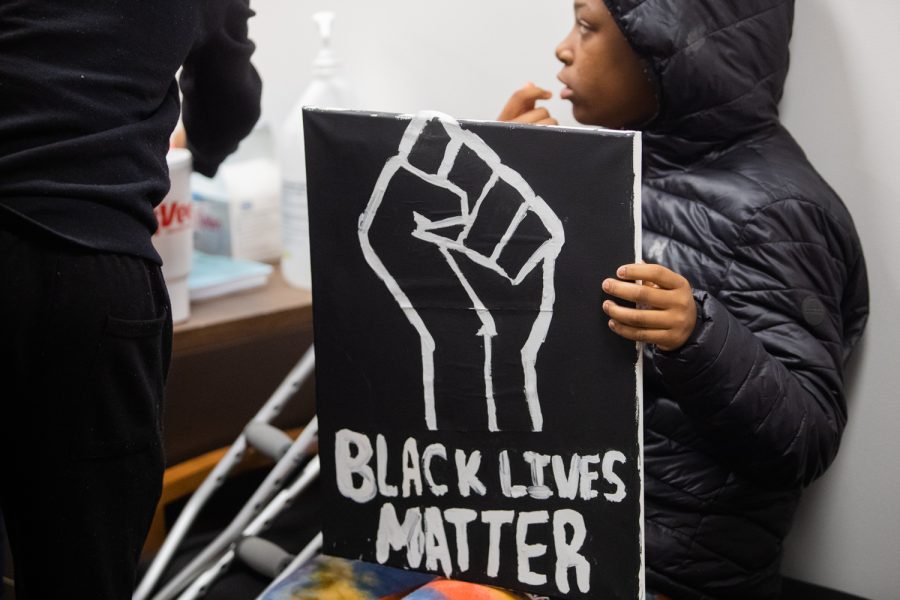 A protester holds a sign at a meeting of the Board of Directors at the Iowa City Community School District Administration Building in Iowa City Tuesday, Nov. 9, 2021. Community members protested after a video surfaced on social media of an Iowa City West High School student using a racial slur and blackface. 