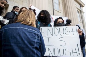 Mayasa Hamid holds a sign that reads “Enough is Enough” in front of an Old Capitol Museum employee asking students to move during a protest against racial discrimination throughout the Iowa City Public School District in Iowa City on Friday, Nov. 19, 2021. The employee wanted the students to move because they were blocking access. “That is completely understandable, however, her attitude was very uncomfortable,” Hamid said. “This is a peaceful protest and we don’t want to do block anyone from doing anything. We’re just here to remind you Black Lives Matter.” 