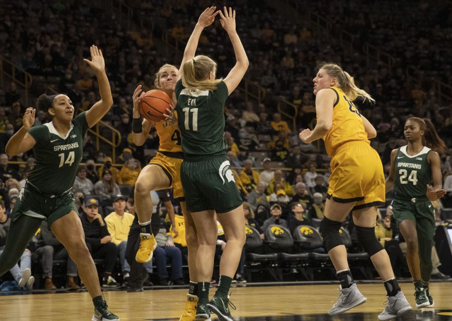 Iowa guard Kylie Feuerbach drives to the basket and is found by Michigan State forward Taiyier Parks. Feuerbach finished with 4 points during a women’s basketball game between No. 9 Iowa and Michigan State at Carver-Hawkeye Arena in Iowa City on Sunday Dec. 5, 2021. The Hawkeyes defeated the Trojans 88-61. (Dimia Burrell/The Daily Iowan)