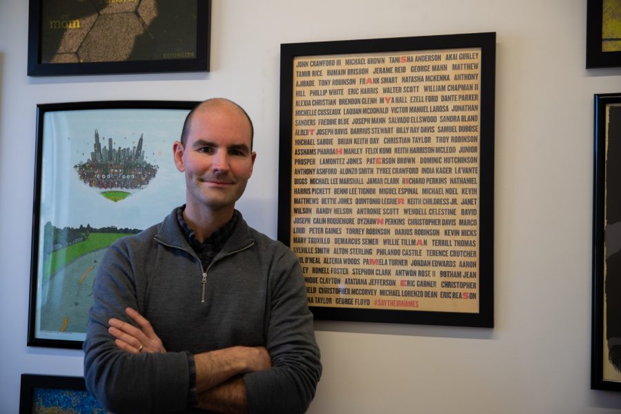Jeremy Swanston poses next to his award winner poster, Say Their Names, in his office at the Visual Arts Building in Iowa City on Dec. 3, 2021. Swanston believes that his piece of art would bring some sort of awareness to this cause, as it was his original motivation.