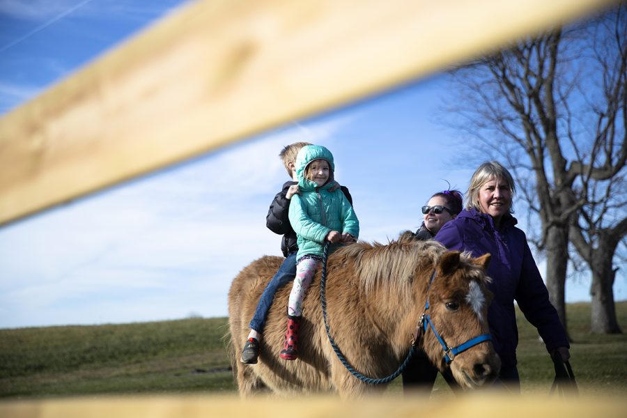 Vera Cavalier smiles while riding a pony as teachers Maya Haukap and Heather Norman guide the pony at the Kinderfarm outside of Iowa City on Thursday, Dec. 2, 2021. 