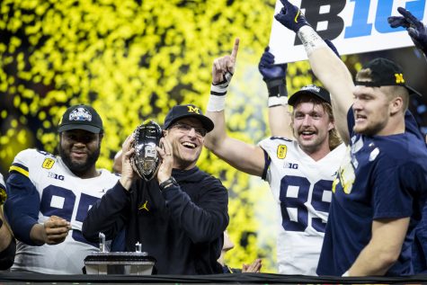 Michigan head coach Jim Harbaugh holds up the Big Ten Championship trophy during the Big Ten Championship game between No. 13 Iowa and No. 2 Michigan at Lucas Oil Stadium in Indianapolis, Indiana, on Saturday, Dec. 4, 2021. The Wolverines became Big Ten Champions after defeating the Hawkeyes, 42-3. 
