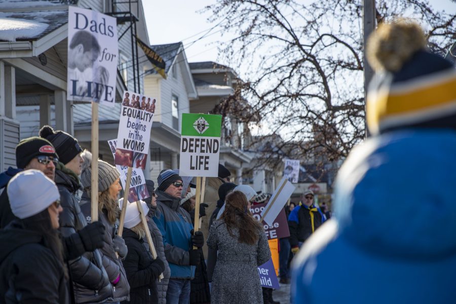 Anti-abortion marchers stand on the sidewalk facing abortion-rights attendees during a protest and counter protest outside the Emma Goldman Clinic for reproductive health care in Iowa City on Saturday, Jan. 22, 2022.