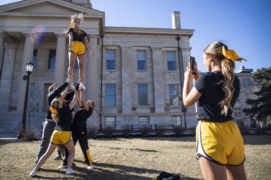 Members of the Iowa Spirit Squad practice a stunt with freshman Sarah Hoffman at the Pentacrest on Sunday, Feb. 20, 2022.  Members of the Iowa Spirit Squad practiced stunts during their lunch break. Temperatures reached the high 50s. “It’s just so nice out,” Spirit Squad member Sarah Hoffman said. 