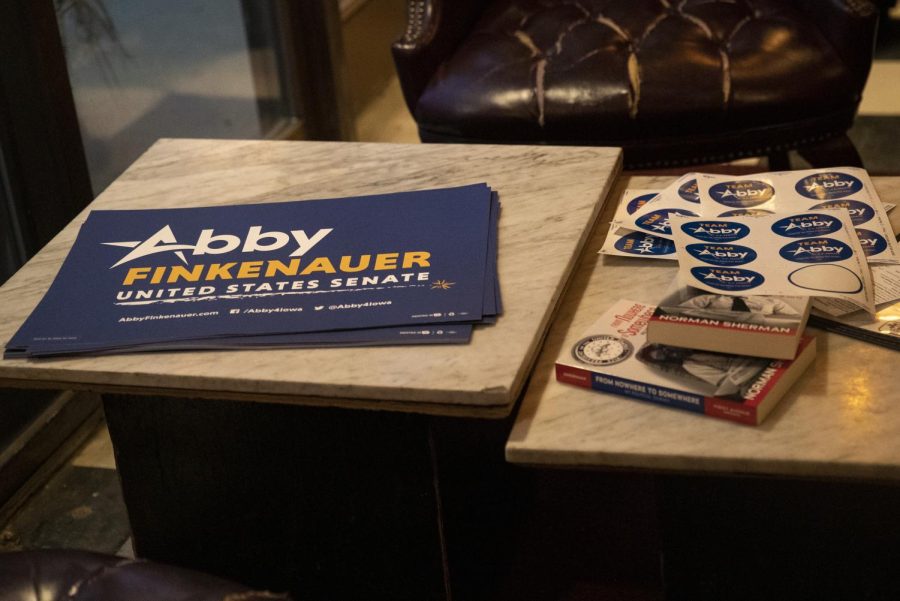Signs and stickers sit on a table at the Abby Finkenauer campaign meet and greet at Sanctuary in Iowa City on Thursday, Mar. 3, 2022. 