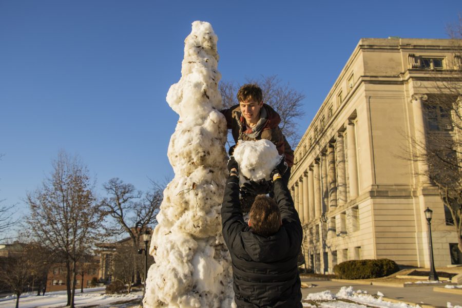 Ean Cummings, a student at the University of Iowa, grabs a snowball from his friend, Logan Clinger, at the Pentacrest on Tuesday, March 8, 2022.