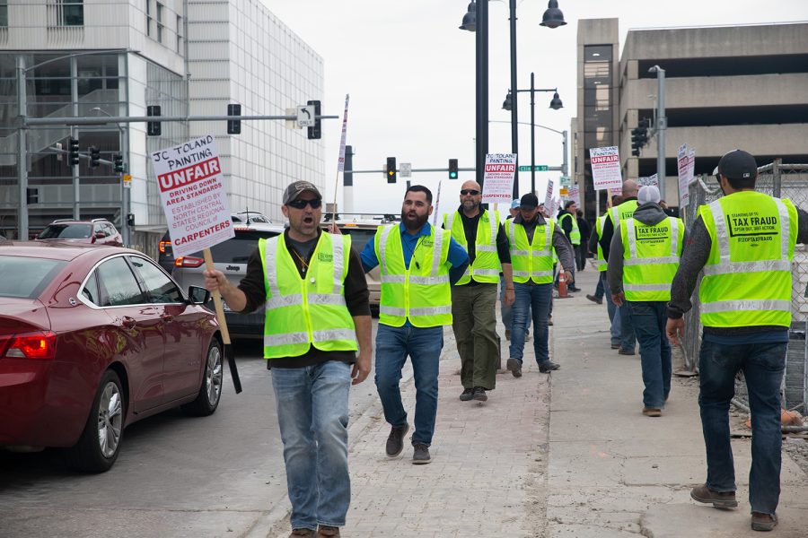 Workers of JC Toland march in front of 120 Burlington St. during an informational picket in downtown Iowa City on Tuesday, April 12 2022. The workers hosted an informational picket to protest JC Tolland’s tax fraud model.